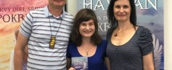 Valentína Sedileková s rodičmi stoja pred roll-upmi knihy Biely havran. Rovnakú knihu drží Valentína v ruke.