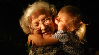 Fotografia malého dievčatka, ktoré objíma svoju babičku. Obe sa usmievajú a sú šťastné.